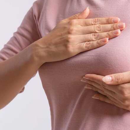 Ženska osoba u majci se drži za dojku - bol u dojkama