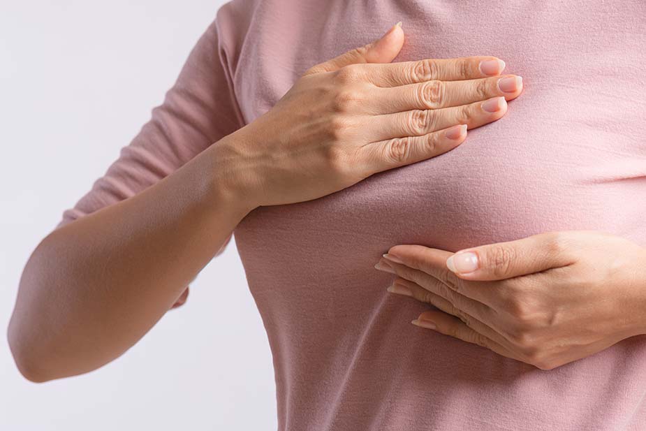 Ženska osoba u majci se drži za dojku - bol u dojkama